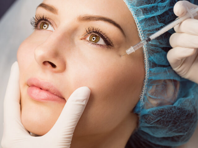Close-up of female patient receiving an injection on her face in clinic